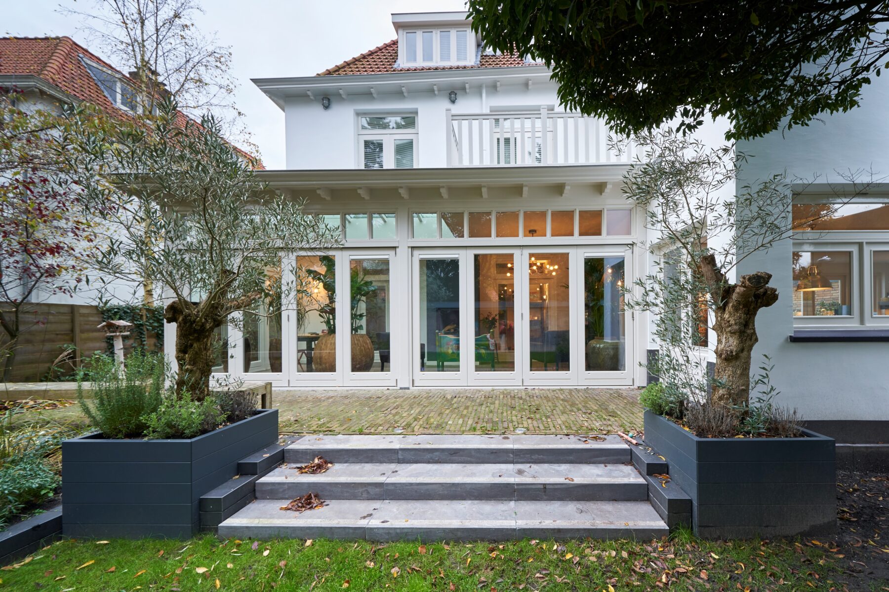 Klassieke serre met harmonicadeuren bij een klassieke huis