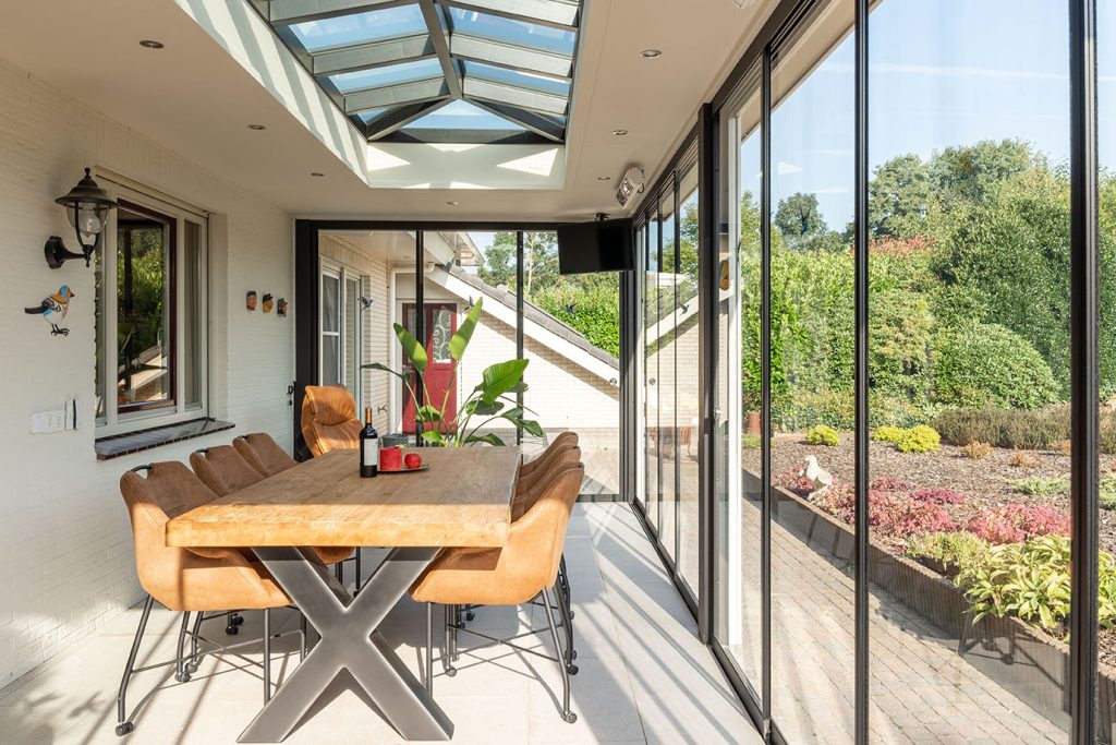 Veranda aan huis met glazen schuifwanden en houten lichtstraat