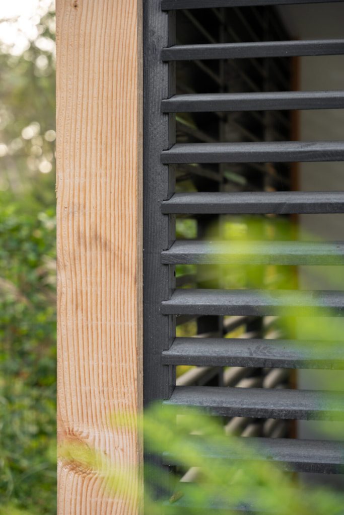Voorbeeld van een houten zwarte lamellenwand in een veranda